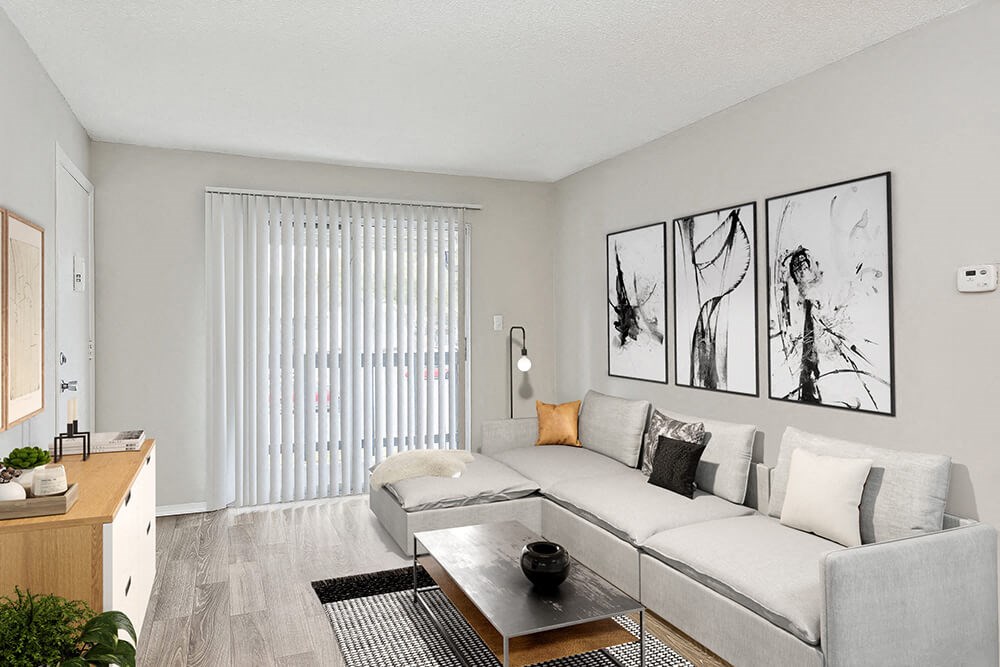 Model Living Room with Wood-Style Flooring and Patio Accessibility at Seven Lakes at Carrollwood Apartments in Tampa, FL.