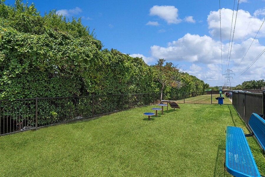Community Dog Park with Agility Equipment and Bench at Bridges at Deer Run Apartments in Dallas, TX.