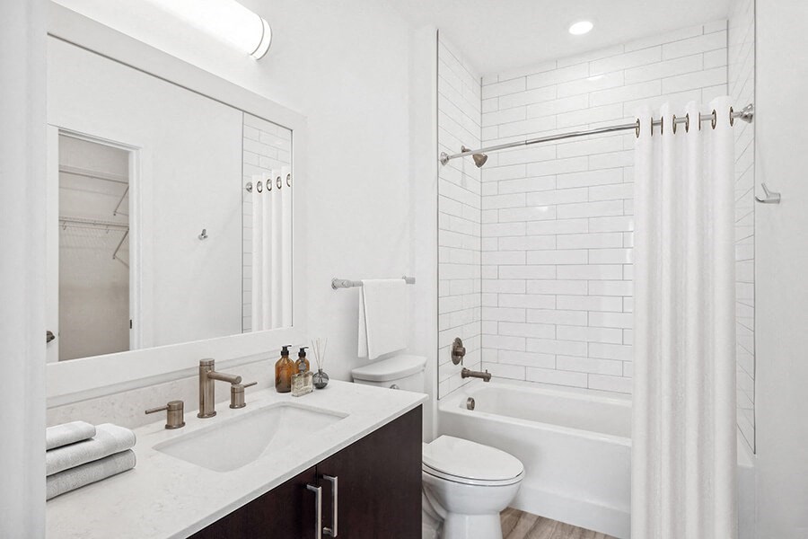 Model Bathroom with Dark Cabinets, Wood-Style Flooring and Shower/Tub at Stella Apartments located in New Carrollton, MD.