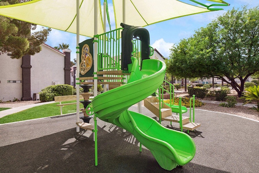 Community Playground with a Slide and Green Canopy at Meadow Ridge Apartments in Las Vegas, NV.