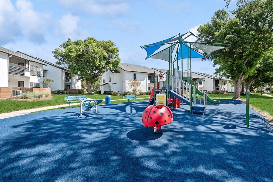 Community Playground with Slide and Blue Canopy at Rosehill Preserve Apartments in Orlando, FL.