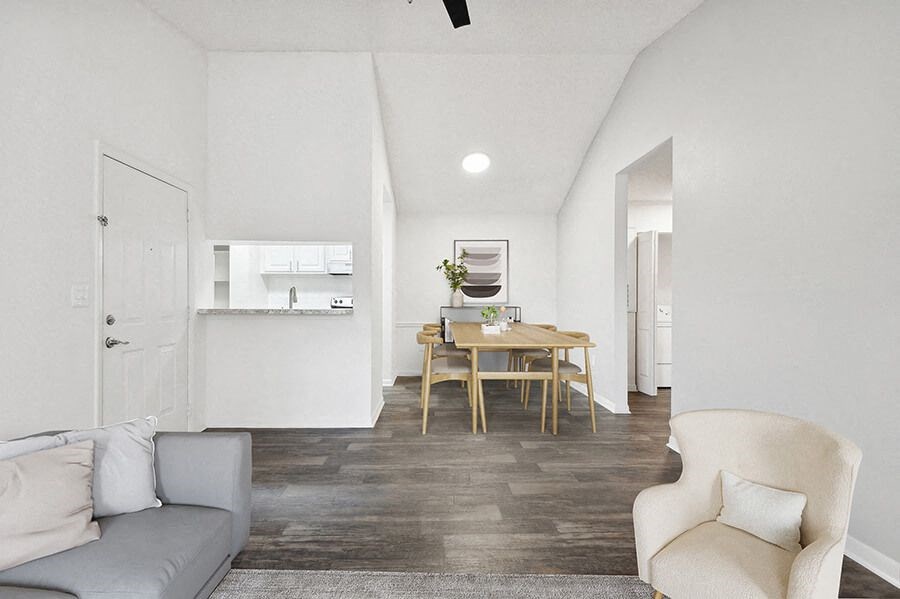 Model Living Room with Wood-Style Flooring and View of Kitchen/Dining Area at Rosehill Preserve Apartments located in Orlando, FL.