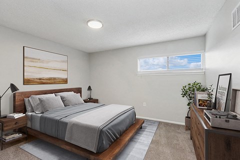 Pet-Friendly Apartments in Kansas City, MO - Parc at Creekside Apartments - Spacious Bedroom With Wood Platform Bed, Nightstands, Lamps, Soft Carpet, Wall Art, Ceiling Light, and Windows.