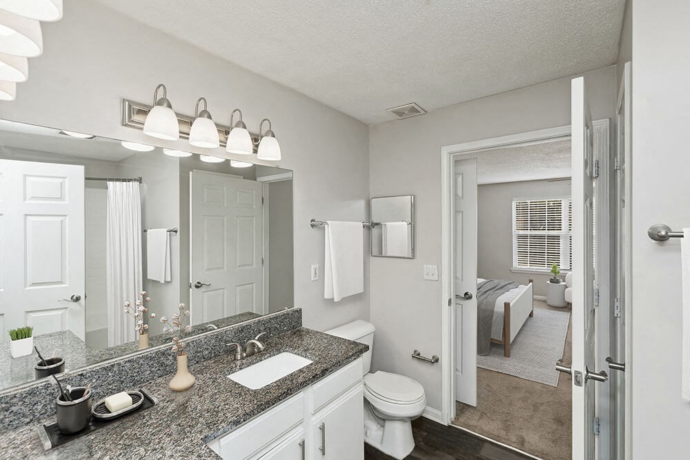 Model Bathroom with White Cabinets and Wood-Style Flooring at Shadow Ridge Apartments in Riverdale, GA.