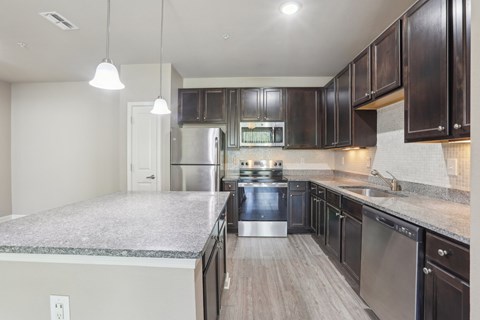 A modern kitchen with dark wood cabinets and stainless steel appliances.