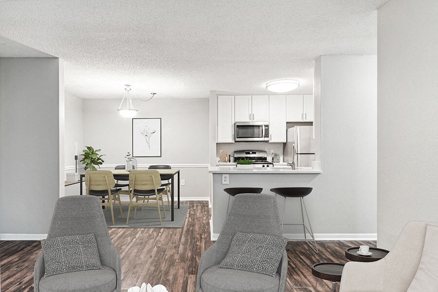 Model Living Room with Wood-Style Flooring and View of Kitchen/Dining Area at Commons at Haynes Farm Apartments in Shrewsbury, MA.