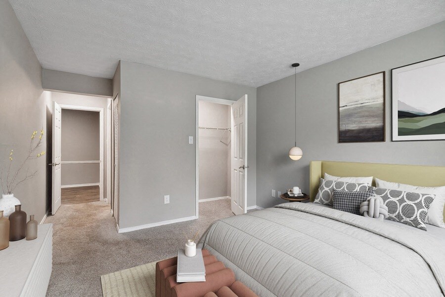 Model apartment bedroom with a large bed and a walk in closet