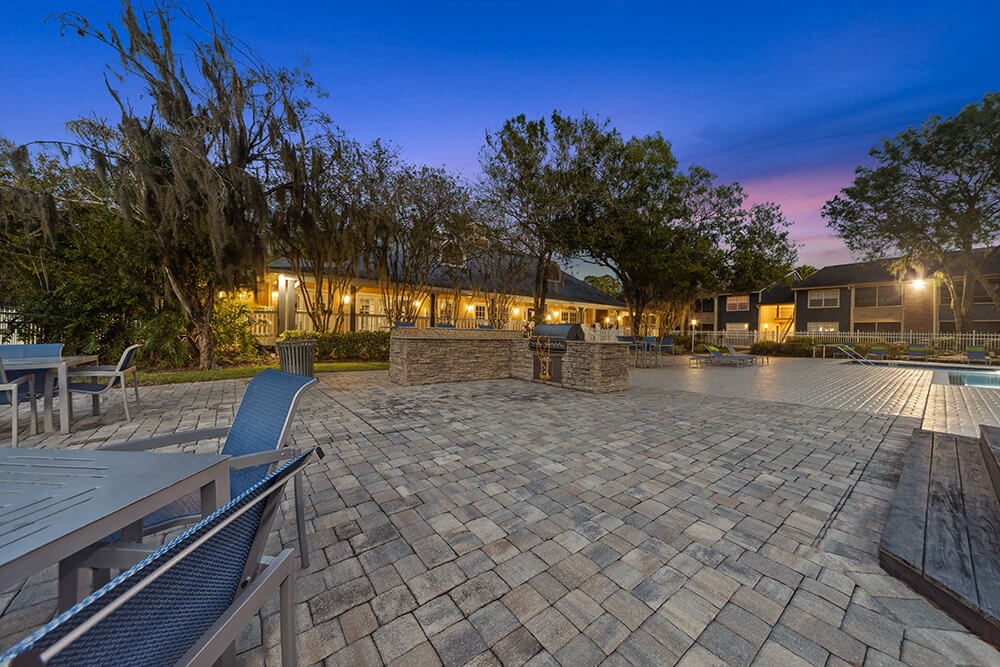 Outdoor BBQ Area with Furniture and Pool View at Walden Lake Apartments in Plant City, FL.