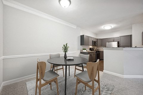 Model Dining Room with Carpet and View of Kitchen at Dulles Green Apartments located in Herndon, VA.