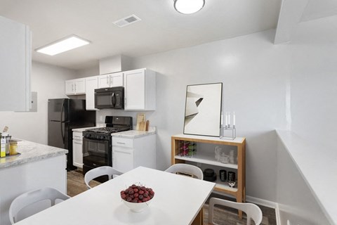 a kitchen and dining room with white cabinets and black appliances and a white table