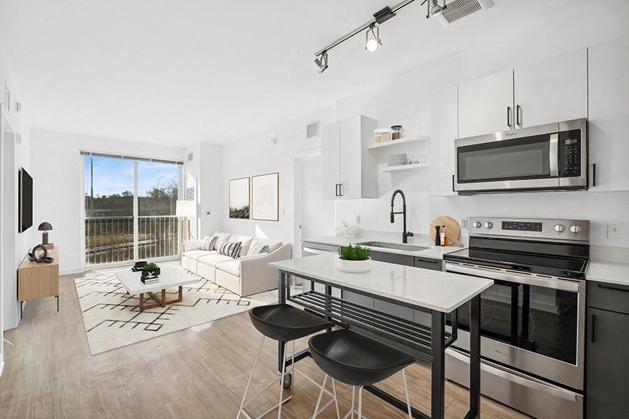 Model Kitchen with Dark Cabinets, Wood-Style Flooring and View of Living Room at Stella Apartments located in New Carrollton, MD.