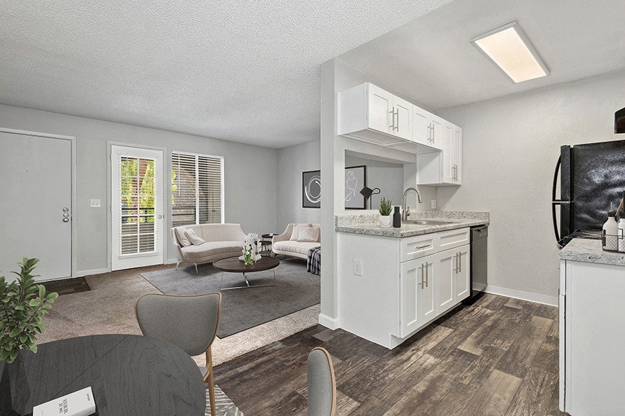 Model Kitchen with White Cabinets and Wood-Style Flooring with View of Dining/Living Room Area at Stillwater Apartments in Glendale, AZ.