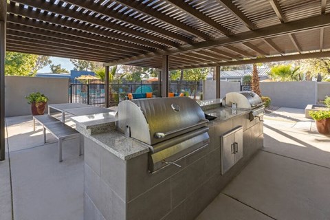 An outdoor kitchen with a grill and a pergola  at Lakeside Casitas in Tucson, AZ