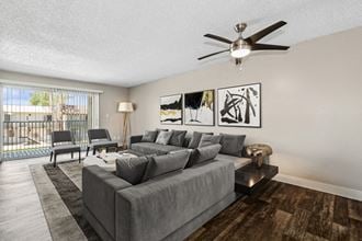 a living room with a large couch and a ceiling fan