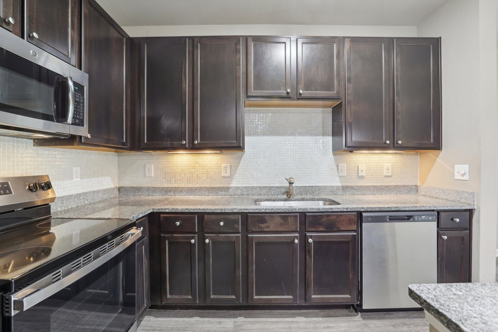 Model kitchen with dark brown cabinets and stainless steel appliances.