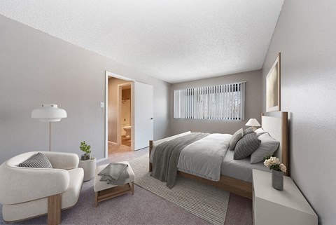 Pet-Friendly Apartments in South Denver, CO - Bridges at 9 Mile Station - A Bedroom With Neutral Bedding, Cozy Accent Chair, Soft Carpet, And Wide Window Blinds.