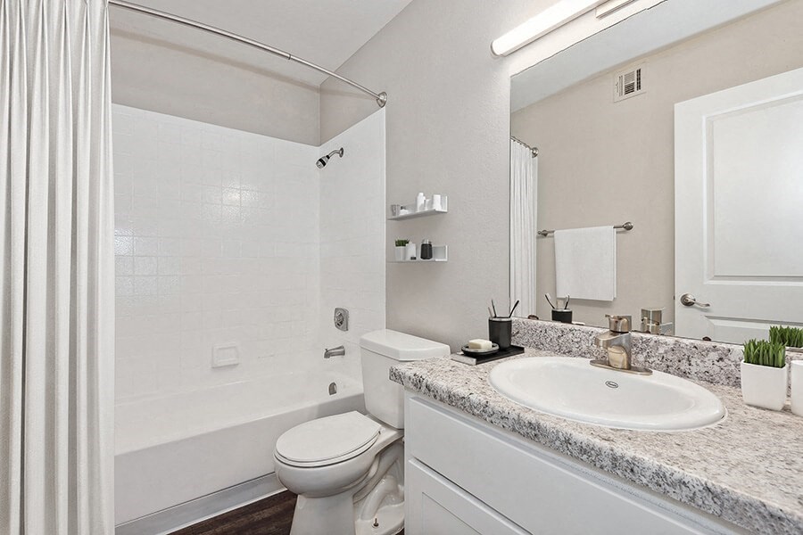 Model Bathroom with White Cabinets, Wood-Style Flooring and Shower/Tub at Peaks on 4th Apartments in Avondale, AZ.