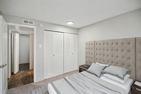 a bedroom with white walls and a white bed with gray pillows