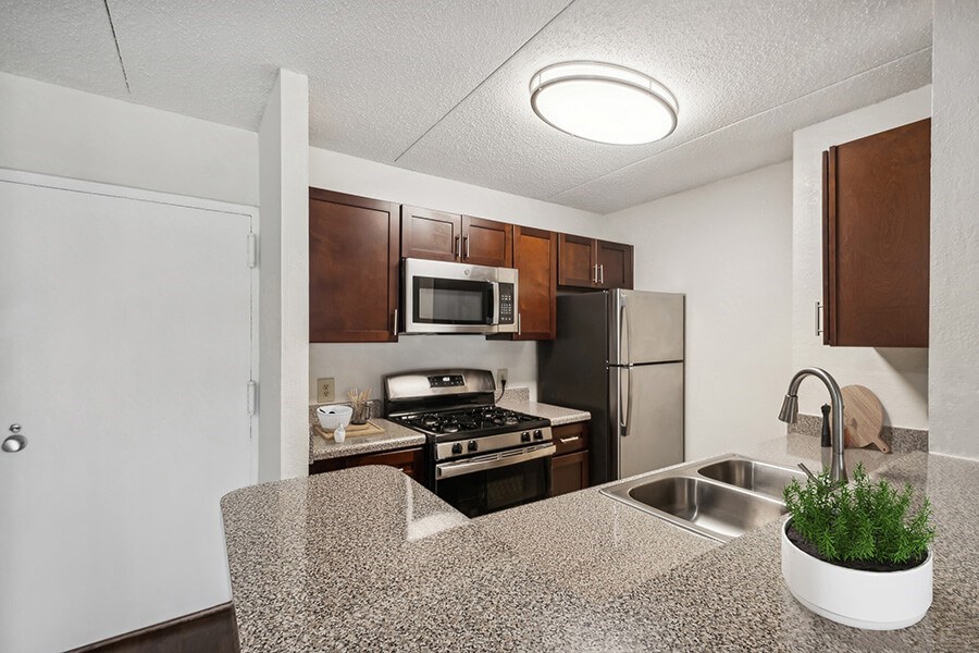 Model Kitchen with Dark Wood Cabinets & Wood-Style Flooring at Mason Van Dorn Apartments located in Alexandria, VA.