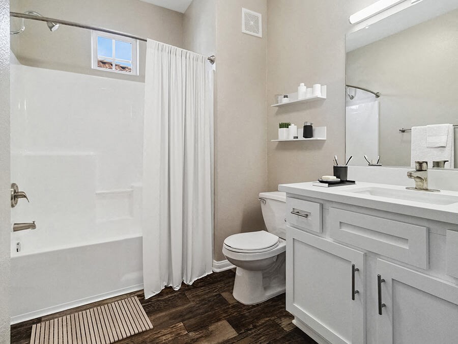 Model Bathroom with White Cabinets, Wood-Style Flooring & Shower/Tub at Reserve at Rancho Apartments located in Moreno Valley, CA.