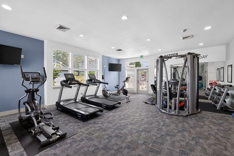 A gym with treadmills, elliptical machines, and other exercise equipment.