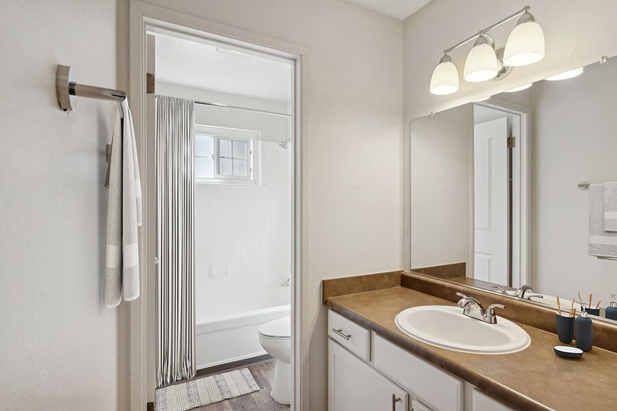 Model Bathroom with White Cabinets, Wood-Style Flooring and Shower/Tub at Los Gatos Landing Apartments located in San Jose, CA.