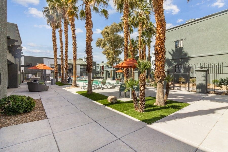 a courtyard with palm trees and a building in the background