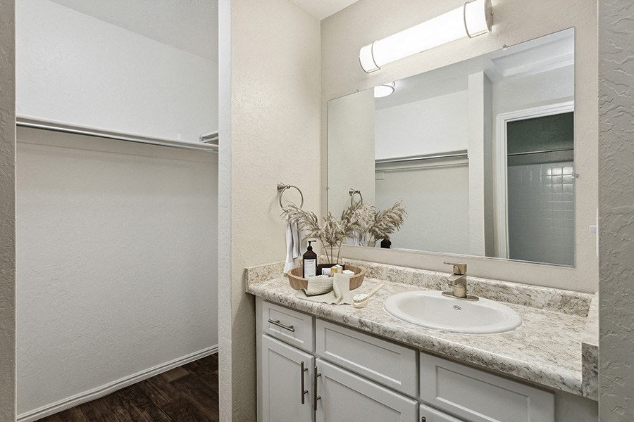 Model Bathroom with White Cabinets, Wood-Style Flooring & Closet at Broadmoor Village Apartments in Salt Lake City, UT.