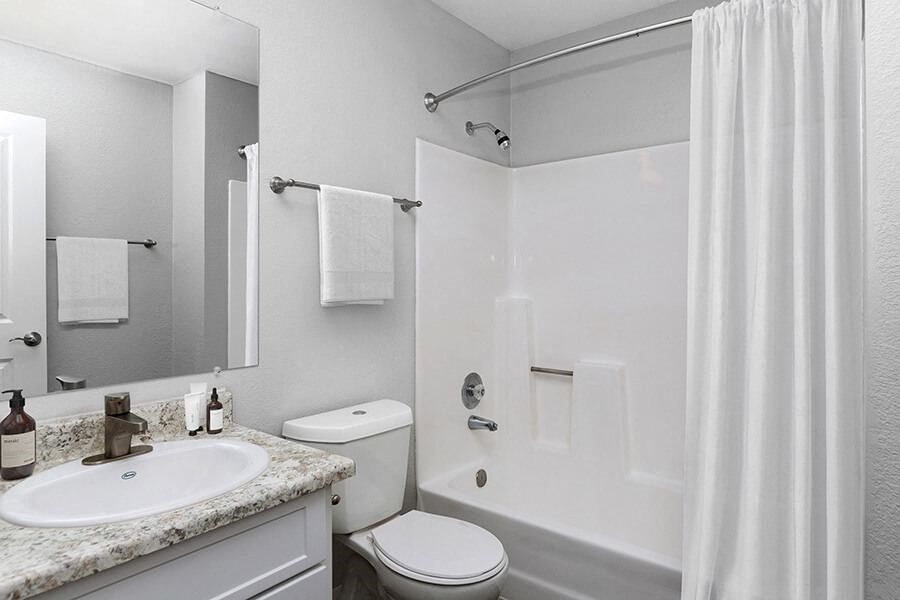Model Bathroom with White Cabinets, Wood-Style Flooring and Shower/Tub at The Meritage Apartments in Vallejo, CA.