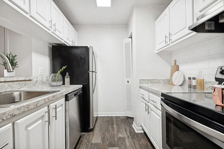 Model Kitchen with Wood-Style Flooring and White Cabinets at Rosehill Preserve Apartments located in Orlando, FL.