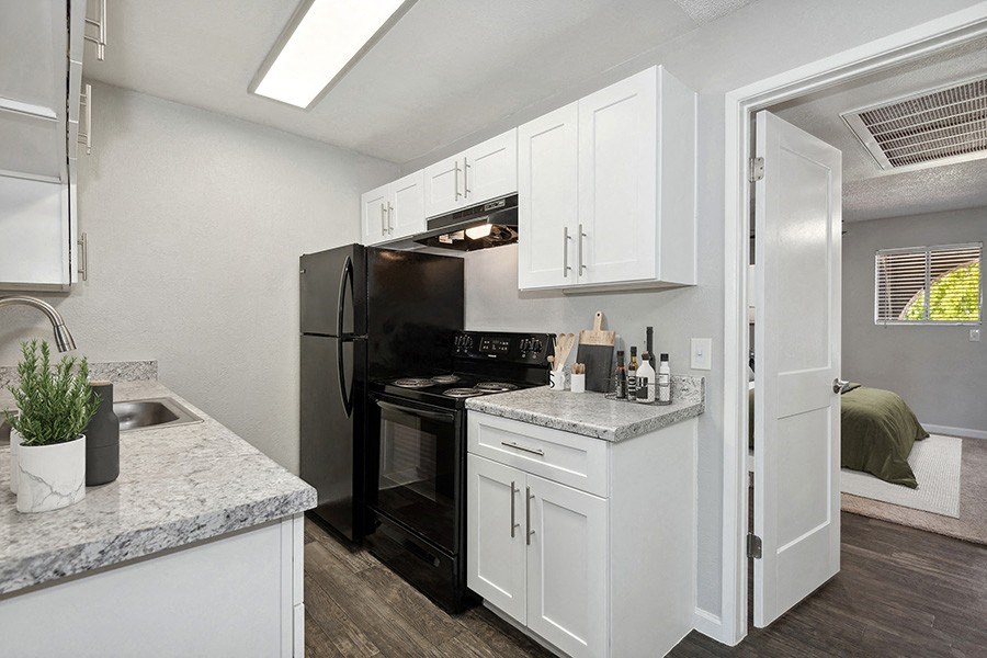 Model Kitchen with White Cabinets and Wood-Style Flooring with Bedroom Entrance at Stillwater Apartments in Glendale, AZ.