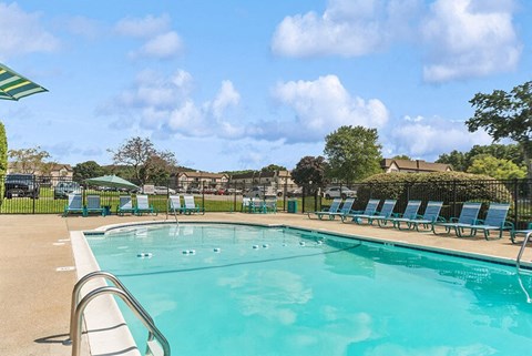 2-Bedroom Apartments in Marlborough, MA - Meadows at Marlborough - Outdoor Swimming Pool With Clear Blue Water, Sundeck Lounge Chairs, Green Umbrellas, And Fenced Courtyard.