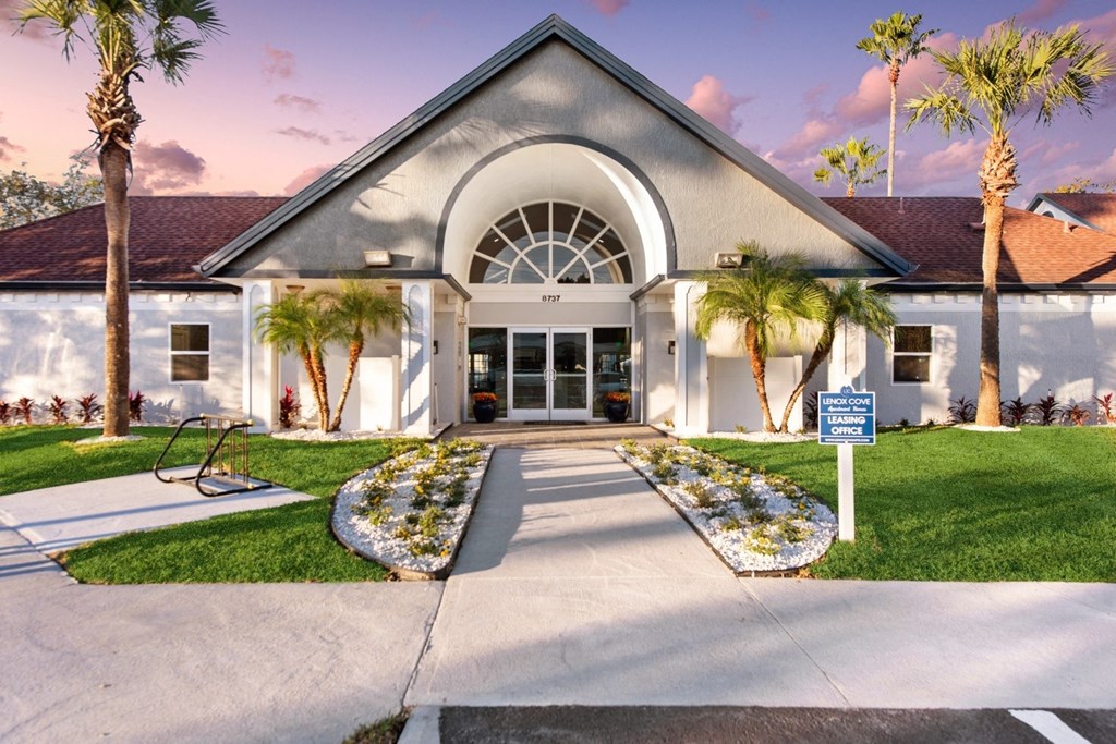 the front of a building with palm trees and a blue and white sign