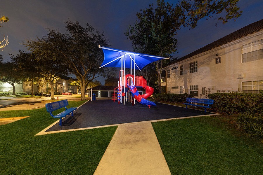 Community Playground with Slide and Blue Canopy at Vinings at Hunter's Green Apartments in Tampa, FL.