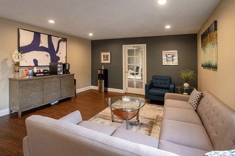 A living room with a grey couch and a glass coffee table.