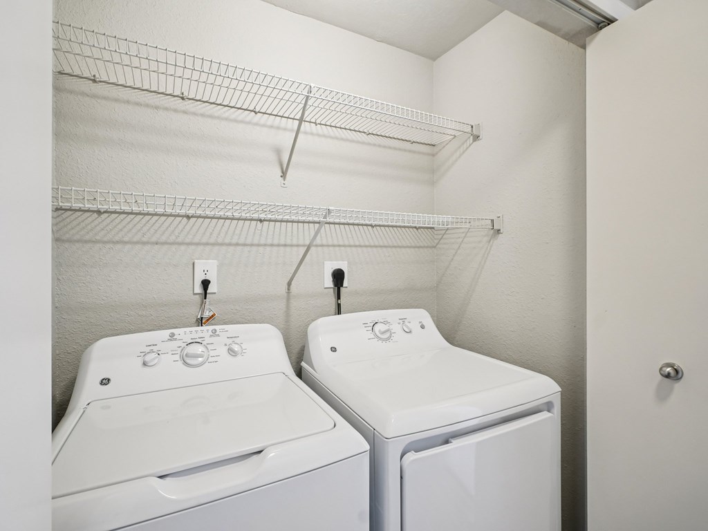 Two white front loading washing machines in a laundry room.