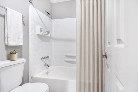 A white bathroom with a towel hanging on the towel rack.