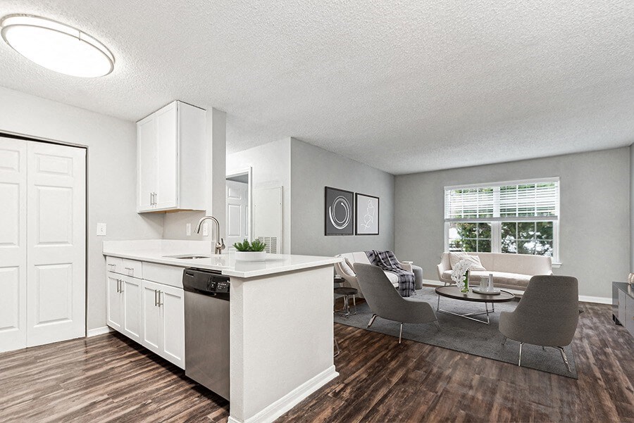 Model Kitchen with White Cabinets, Wood-Style Flooring and View of Living Room at Commons at Haynes Farm Apartments in Shrewsbury, MA.