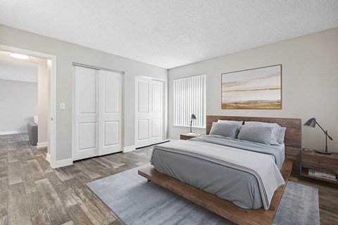 Three-Bedroom Apartments in Avondale, AZ - The Peaks on 4th - A Bedroom With A Platform Bed, Matching Nightstands, Vertical Blinds, Double Closet Doors, And Wood Style Flooring.