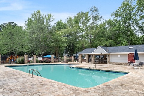 One-Bedroom Apartments in College Park, GA - Brookstone - Resort Style Swimming Pool With Poolside Cabana, Lounge Seating, And Fenced Deck Area Surrounded By Green Landscaping