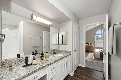 Model Bathroom with White Cabinets and Wood-Style Flooring at Hidden Creek Apartments in Lewisville, TX.