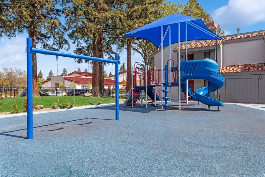 Community Playground with a Slide, Swing Set and Blue Canopy at Creek 2645 Apartments in Sacramento, CA.