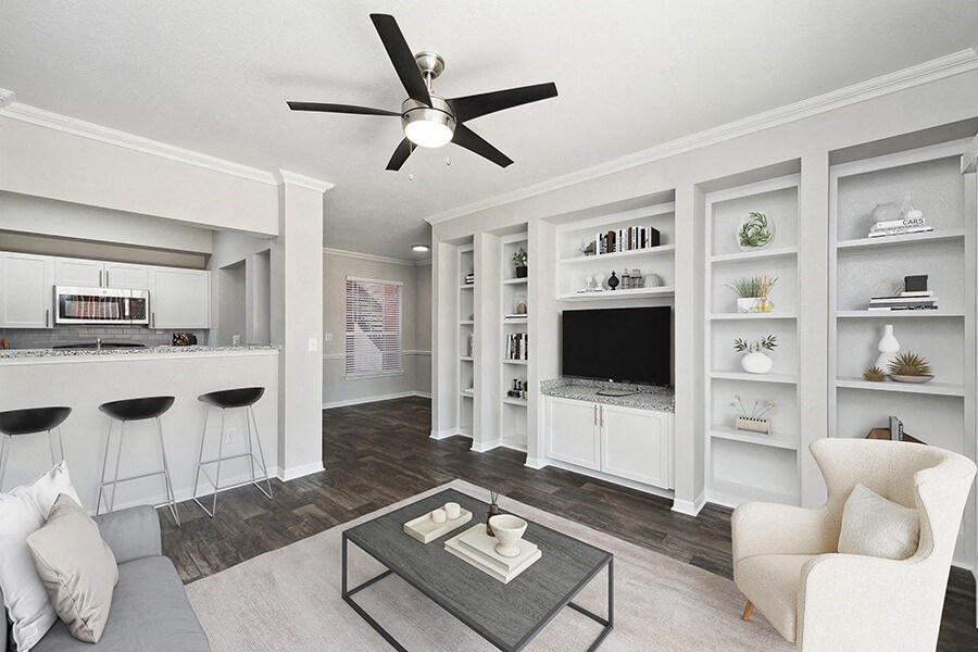 Model Living Room with Wood-Style Flooring, Built in Shelves and View of Kitchen at Chapel Hill Apartments in Lewisville, TX.