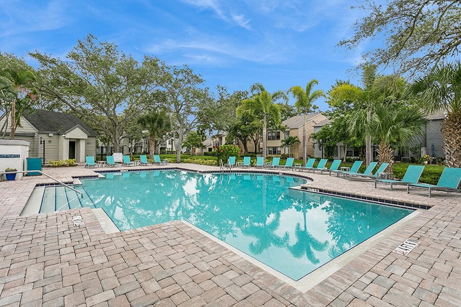 Community Swimming Pool with Pool Furniture at Huntington Place Apartments located in Sarasota, FL.