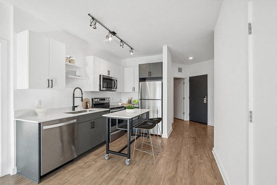 Model Kitchen with Dark Cabinets, Wood-Style Flooring and View of Living Room at Stella Apartments located in New Carrollton, MD.