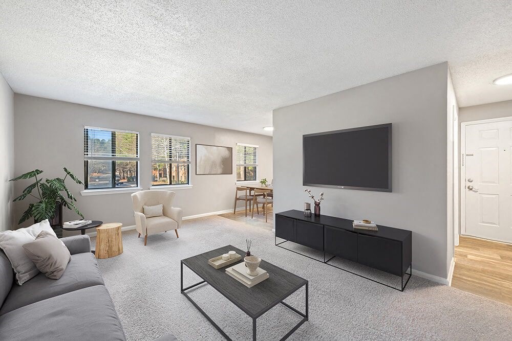 Model Living Room with Carpet and View of Dining Room with Wood-Style Flooring at Spring Forest Apartments in Raleigh, NC.