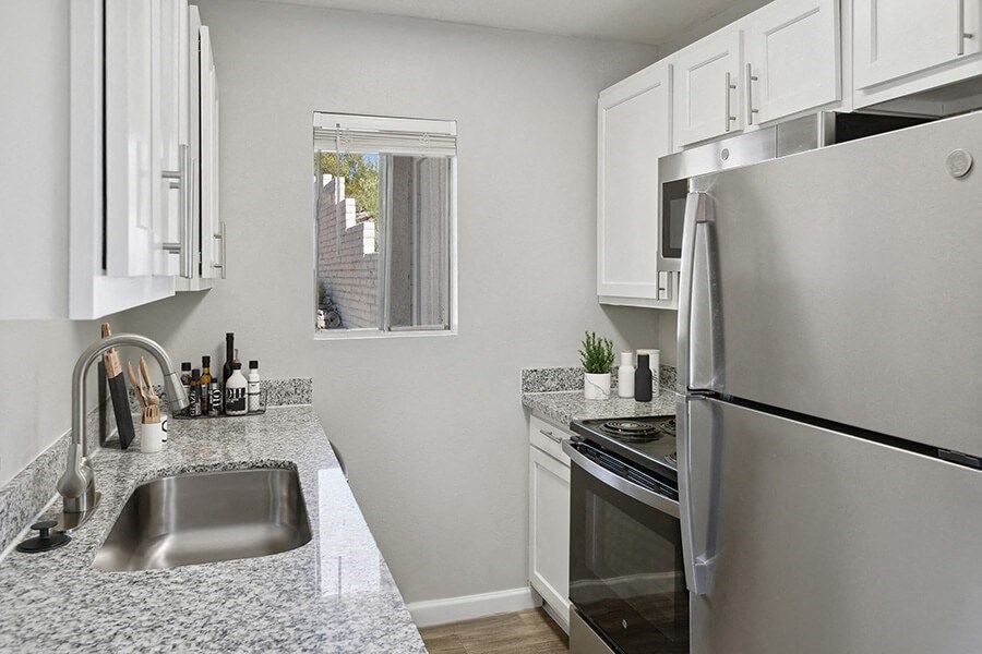 Model Kitchen with White Cabinets and Wood-Style Flooring at Hilands Apartments in Tucson, AZ.
