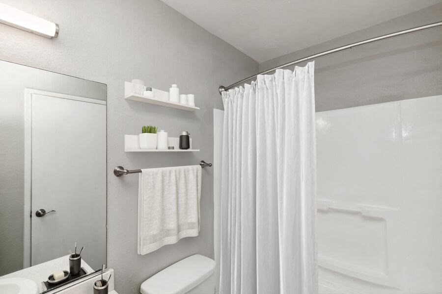 Model apartment bathroom with a shower curtain and a toilet and a sink