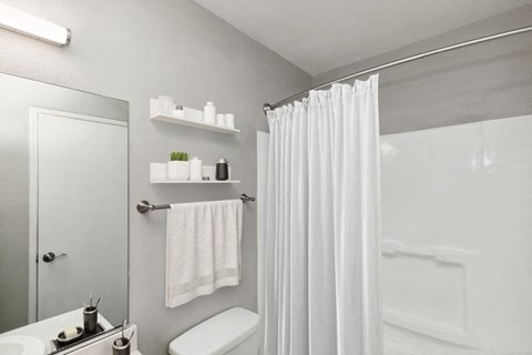 Model apartment bathroom with a shower curtain and a toilet and a sink