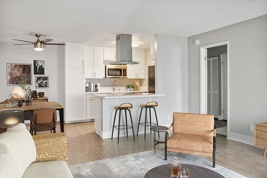 Model Living Room with Wood-Style Flooring and View of Kitchen at Cove La Mesa Apartments located in La Mesa, CA.
